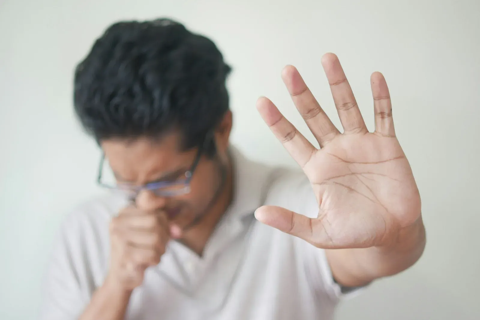 A man holding his hand up in front of his face