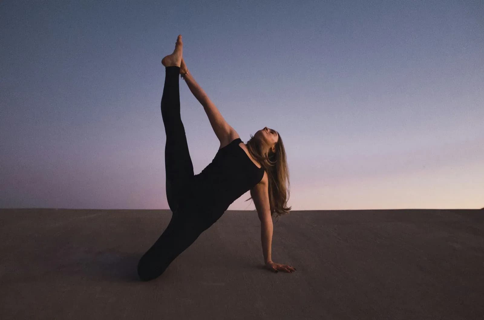 woman holding her left leg high kneeling on floor