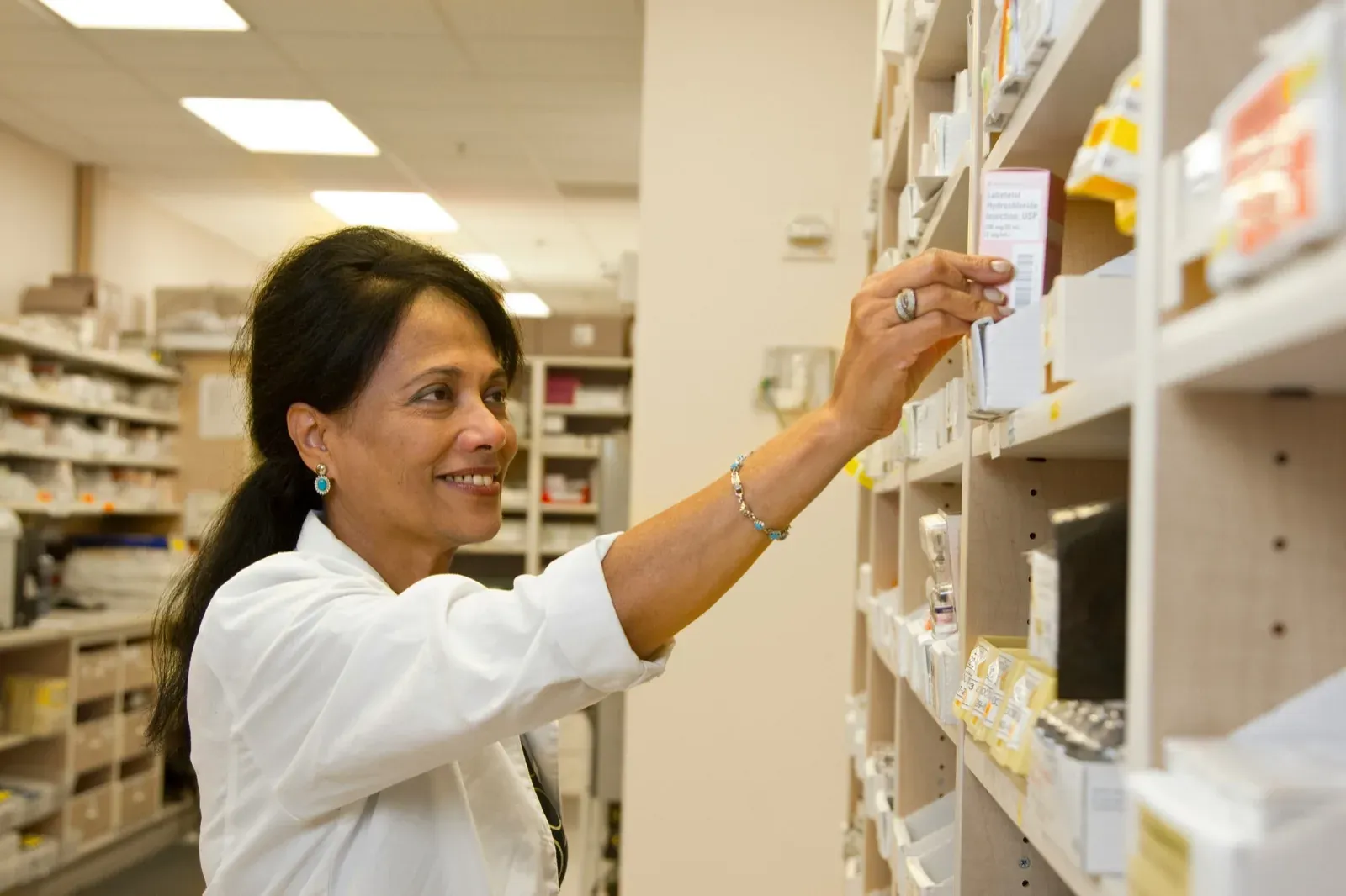 A pharmacist holding a box of medication